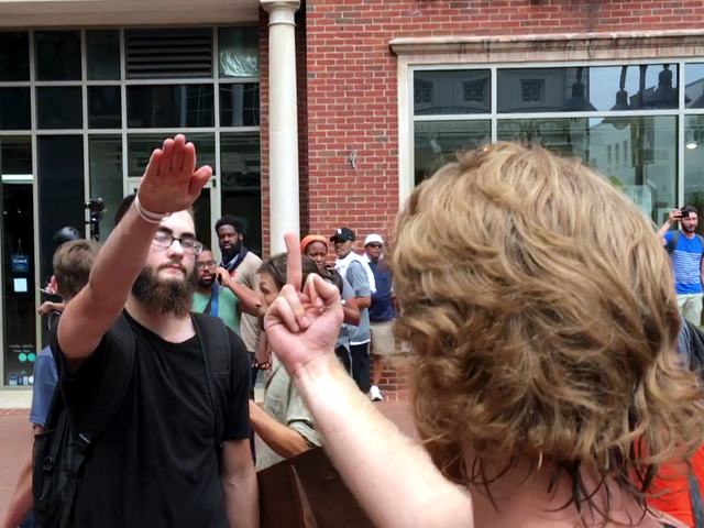 A man gives a Nazi salute, and a woman flicks him off.